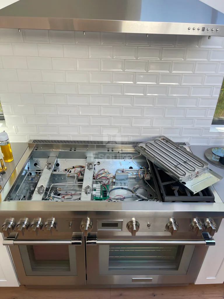 Pro-style range cooktop with the surface lifted showing internal components