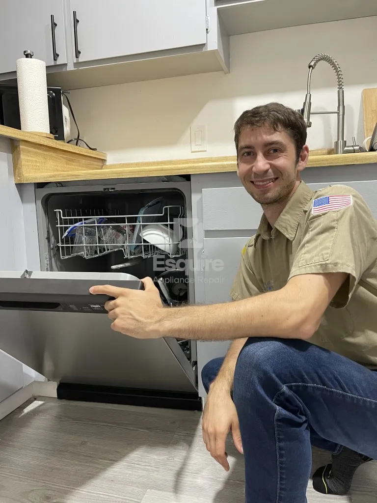 Technician kneeling beside an open dishwasher in an Orange County kitchen